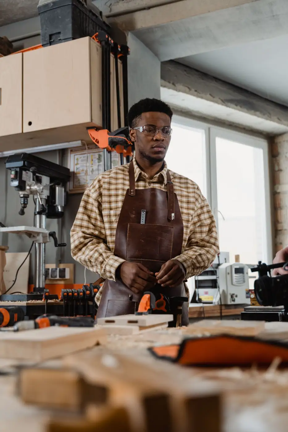 Joiner in apron and safety glasses at a workbench