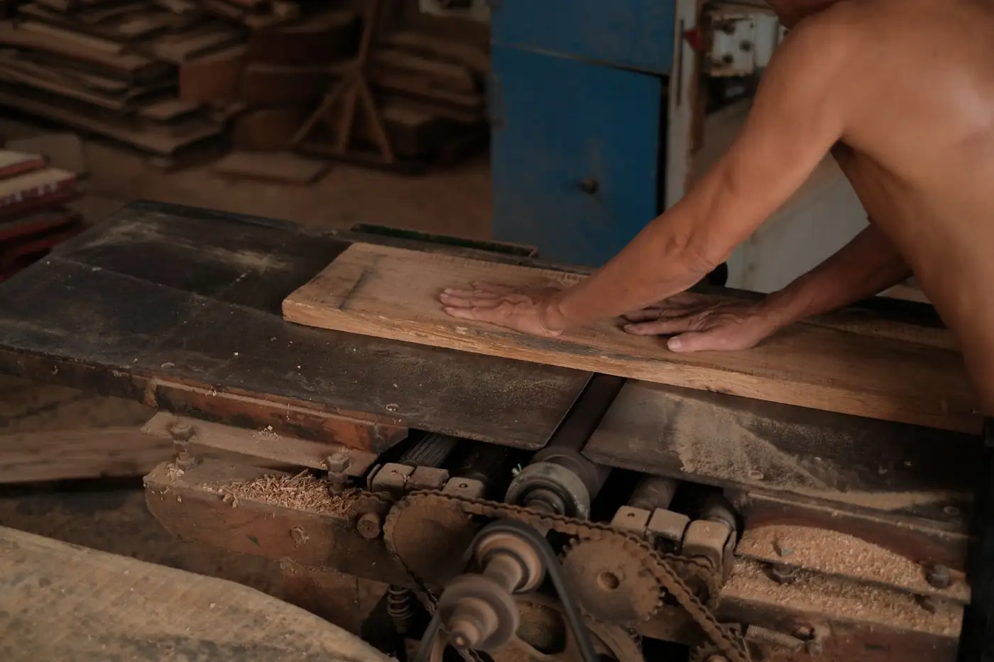 Carpenter feeding timber through a jointer in a workshop