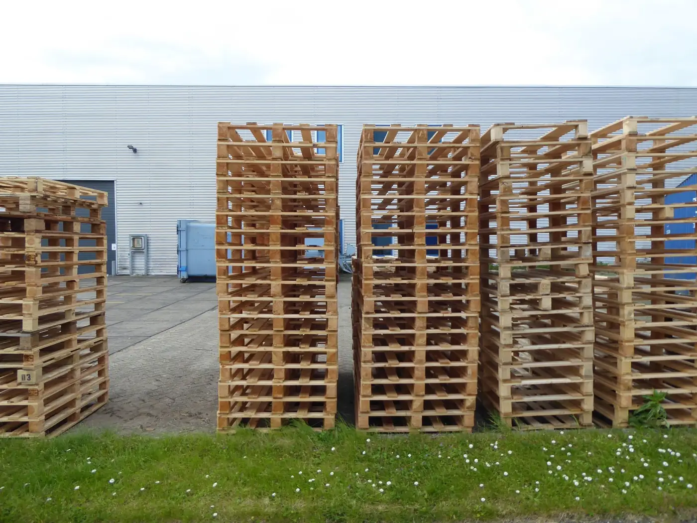 Tall stacks of wooden shipping pallets outside a warehouse