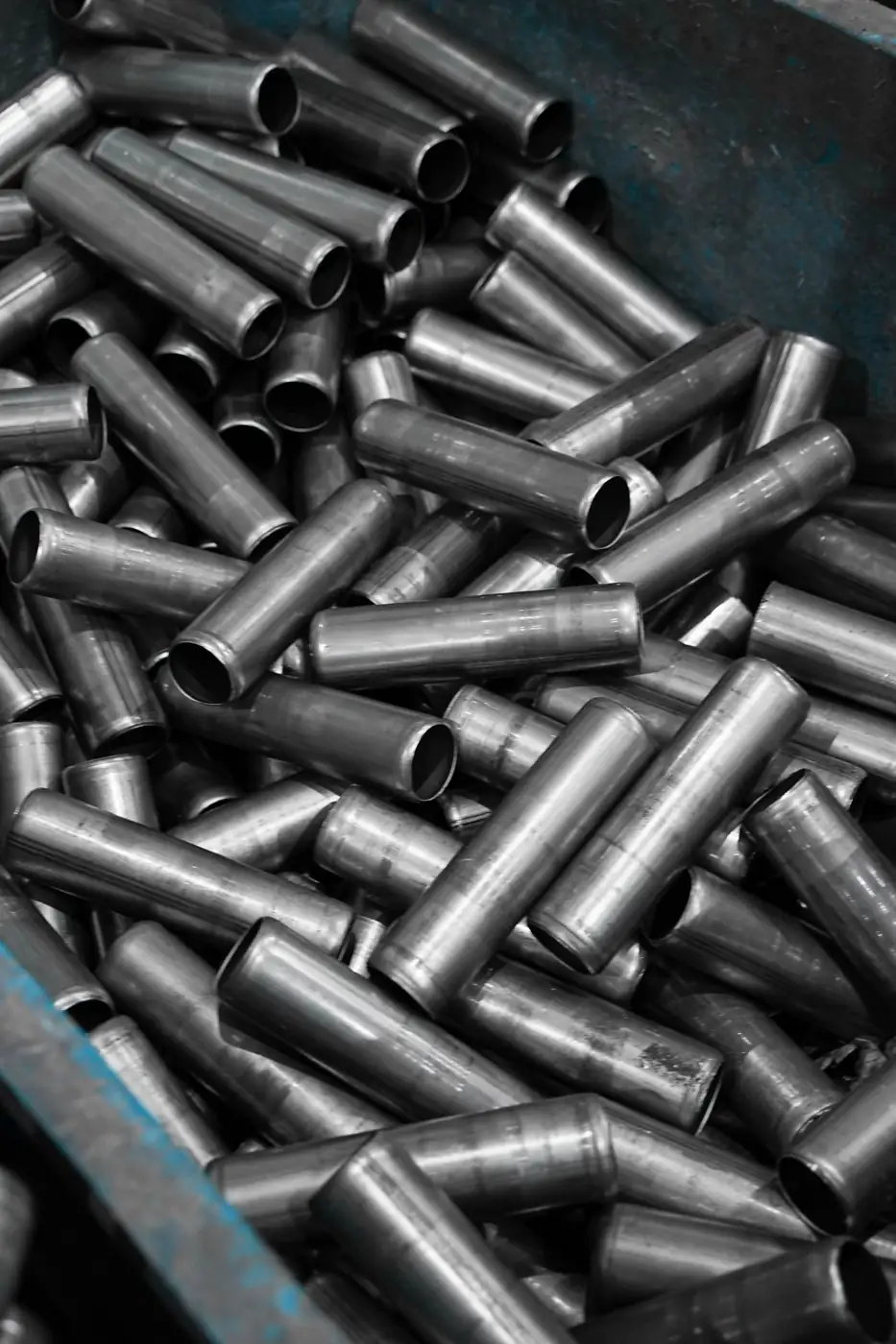 Short steel tubes piled in a blue industrial bin