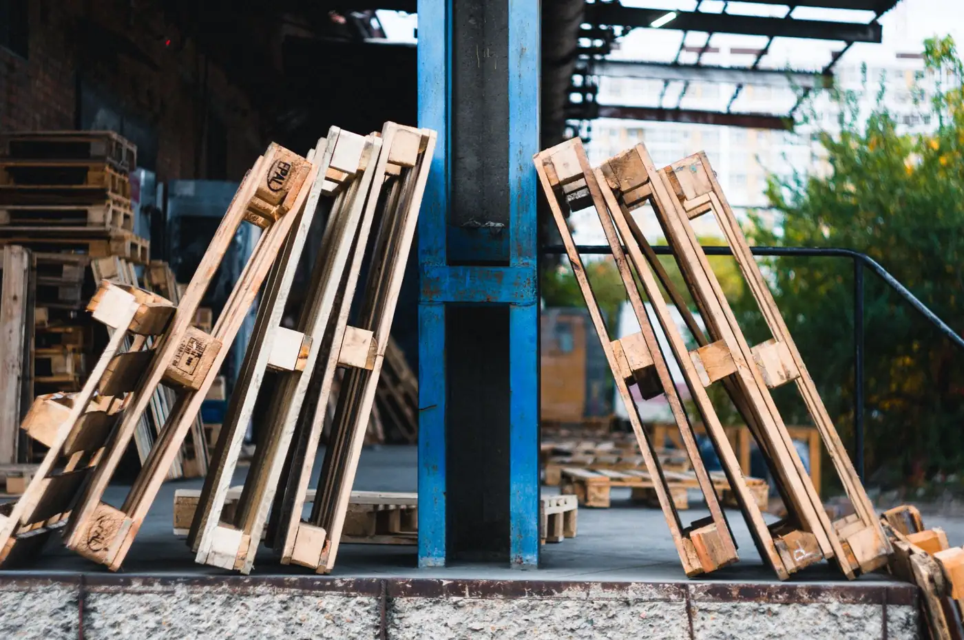 Wooden pallets leaning against a blue warehouse beam